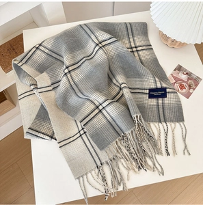 Close-up of gray and beige plaid scarf showing soft fabric texture and fringe edges
