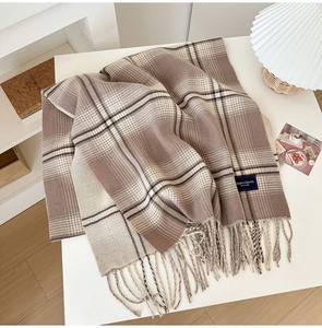 Detailed texture of brown plaid scarf with fringe and Elegant Classic fabric label