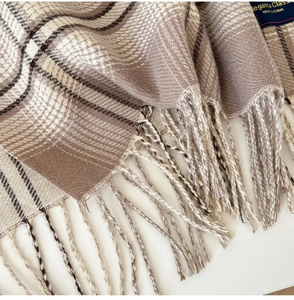 Detail of plaid scarf with soft fringe tassels and neutral check pattern fabric