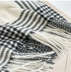 Gros plan d'une écharpe pied-de-poule noire et blanche avec franges et texture douce