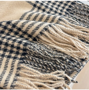 Gros plan sur la texture épaisse de l'écharpe pied-de-poule beige et noir à franges