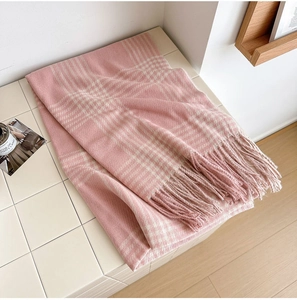 Gros plan d'une écharpe à carreaux rose et crème avec texture cachemire et longues franges