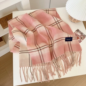 Pink and beige checkered plaid scarf with soft fringe tassels on a minimalist white desk