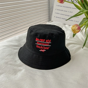 Detail of a black cotton bucket hat featuring embroidered artistic white lettering