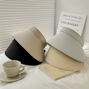 Detail of four colorful wide-brim sun visors with UALABCL labels in a cozy lifestyle setting