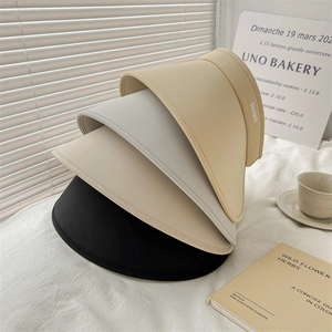 Detailed close-up of wide brim sun visors in black and beige with UALABCI woven labels