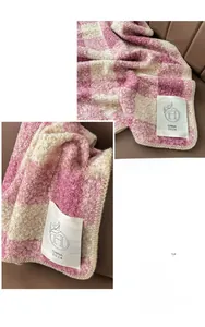 Dettaglio di sciarpa a scacchi rosa e bianco in maglia boucle con etichetta in tessuto