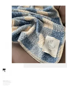 Dettaglio della sciarpa in maglia a quadri blu e grigi con etichetta in primo piano