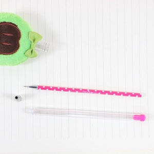 Cute fruit themed plush pen with green cap and bow tie on minimalist notebook background