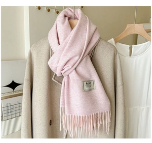 Détail de la texture de l'écharpe rose avec franges et étiquette sur manteau beige