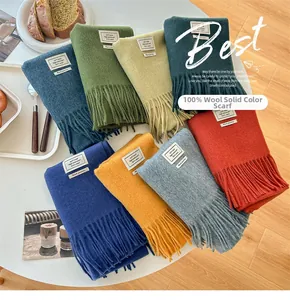 Detailed flat lay of colorful 100% pure wool scarves with fringe on a white table