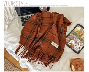Close-up of caramel checkered faux cashmere scarf with elegant fringe on white bedding