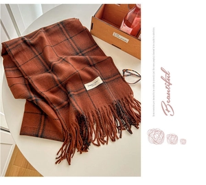 Detail of rust-red plaid scarf featuring elegant tassel fringe and warm cashmere feel fabric
