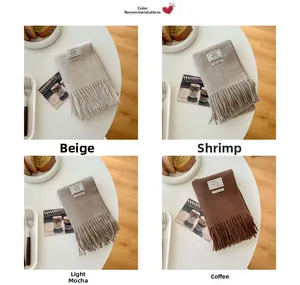Flat lay of wool scarves in beige and mocha tones with elegant tassels on a cozy table