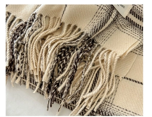 Detailed view of beige plaid scarf showing high-quality fiber texture and fringe edges