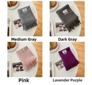 Detail view of wool scarves in grey, pink and purple with fringe and woven labels
