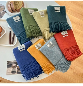 Flat lay of multiple color 100% wool scarves with fringe on a minimalist table