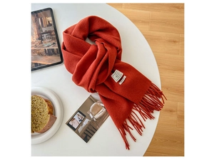 Detail of 100 percent wool orange scarf showing soft texture and fringe on white table