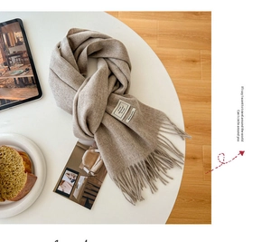 Detail view of oatmeal wool scarf texture with fringe and 100% wool brand label