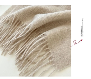 Macro shot of oatmeal wool scarf fabric showing soft brushed texture and fringe details