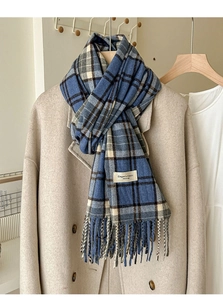 Détail d'une écharpe à carreaux bleu et gris avec franges sur un manteau en laine beige