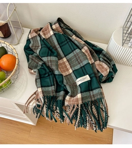Détail d'une écharpe à carreaux vert et marron avec franges et texture douce