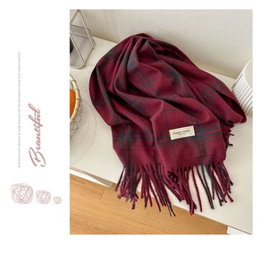 Détail d'une écharpe à carreaux rouge foncé douce avec glands et étiquette Elegant & Classic