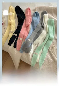 Dettaglio della trama in maglia di sciarpe colorate con etichetta Vegetable