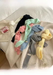 Dettaglio di sciarpe in maglia colorate che mostra la trama morbida e l'etichetta