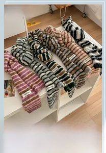 Close-up of assorted striped knitted scarves with plush texture and woven logo labels
