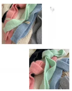 Dettaglio di morbide sciarpe in maglia peluche con etichette in vari colori pastello