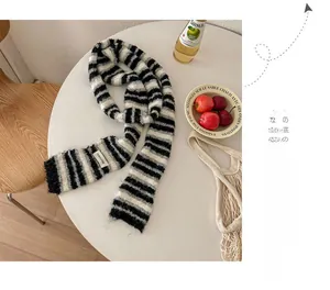 Detailed knit texture of a black and white striped scarf on a minimalist table