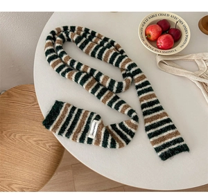 Detail shot of a striped knitted scarf with woven label on a white table set
