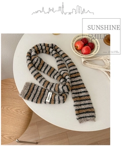Close-up of soft striped knit scarf with frayed edges on a cozy wooden table set