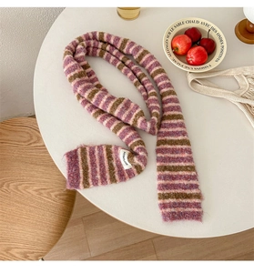Detail of pink and beige striped knit scarf on white table with cozy home decor