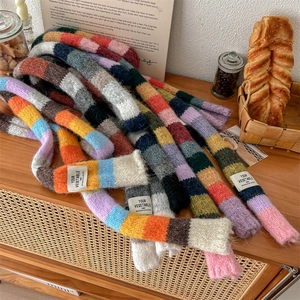 Rainbow striped knit scarf with colorful patchwork and soft chunky yarn on a wooden surface