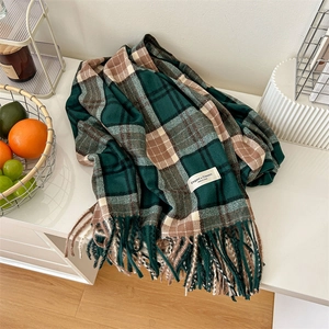 Écharpe épaisse à carreaux avec pompons marron et vert dans un décor hivernal