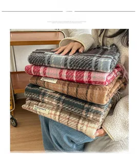 Dettaglio di sciarpe a quadri spesse con lunghe nappe ed etichetta tessuta di stile