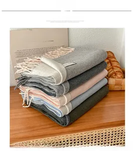Close-up of thick wool blend scarves in various colors with tassels on a wooden table