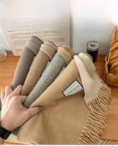 Close-up of wool blend scarf tassels in earthy tones with decorative coffee setting