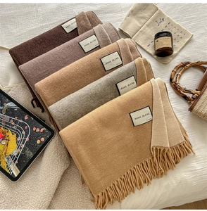 Close-up of wool blend fabric texture and labels on solid color fringed scarves