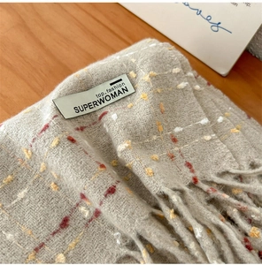 Detailopname van dikke geruite sjaaltextuur met label en franjes aan de rand