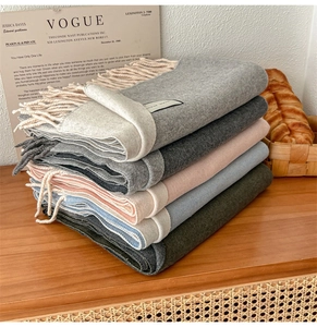 Detail of wool blend scarves with tassels neatly stacked on a wooden table