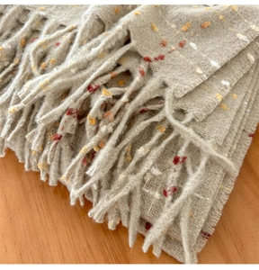 Detailopname van de grijsbeige sjaaltextuur met gekleurde spikkels en zachte franjerand