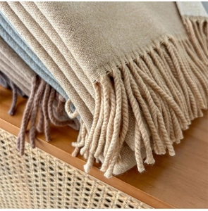 Close-up of wool blend scarves with tassels in beige and grey on a warm wooden background