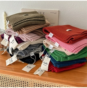 Primo piano di sciarpe in maglia 100% lana di vari colori impilate su un tavolo di legno