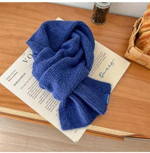 Dettaglio della trama della sciarpa in maglia blu navy con etichetta su legno