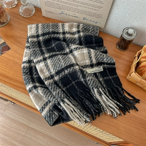 Sciarpa a quadri con nappe in filato bouclé e patch logo su superficie in legno