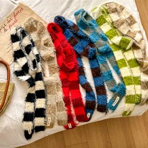 Mise à plat de cinq écharpes en peluche à damier coloré sur un tissu blanc doux