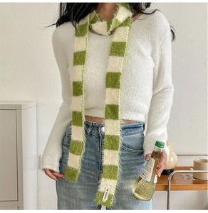 Détail de l'écharpe en peluche à damier vert et blanc avec étiquette KN STUDIO tissée